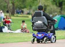 Male in powered wheelchair in park. Occupational Rehab Assessment to help with mobility.