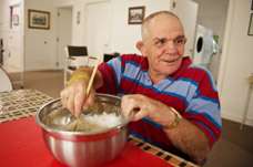 Male sitting in kitchen making a cake. Environmental assessment to help with the home. Rehabilitation for the environment.